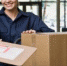 Friendly delivery woman in uniform with stack of cardboard boxes and shipping receipt - Вечер Елабуги